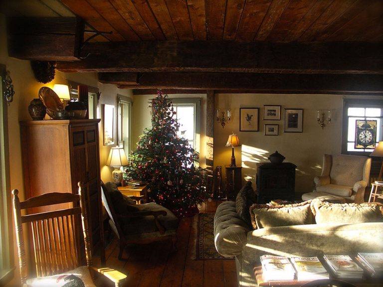 Cozy living room of the inn with rocking chair, plush sofa, wood stove, and lit Christmas tree