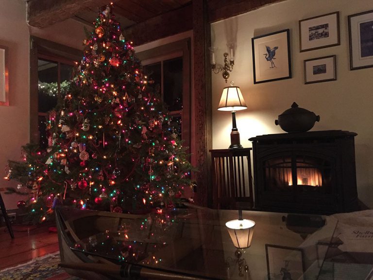Living room of the inn with lit Christmas tree and a fire burning in the wood stove