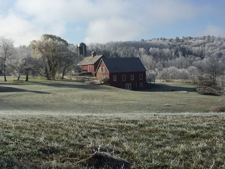 red barn and silo in the fall with frost on the grass and trees