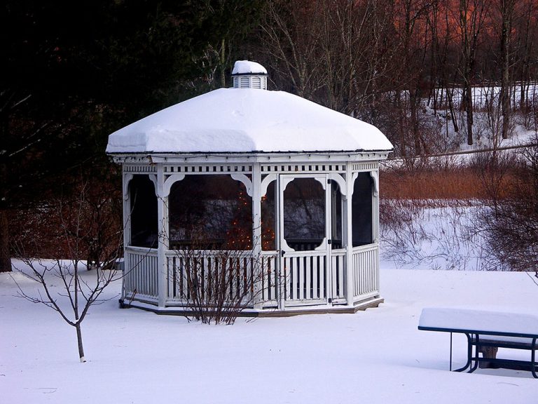 white gazebo in snowy front yard with Christmas tree inside