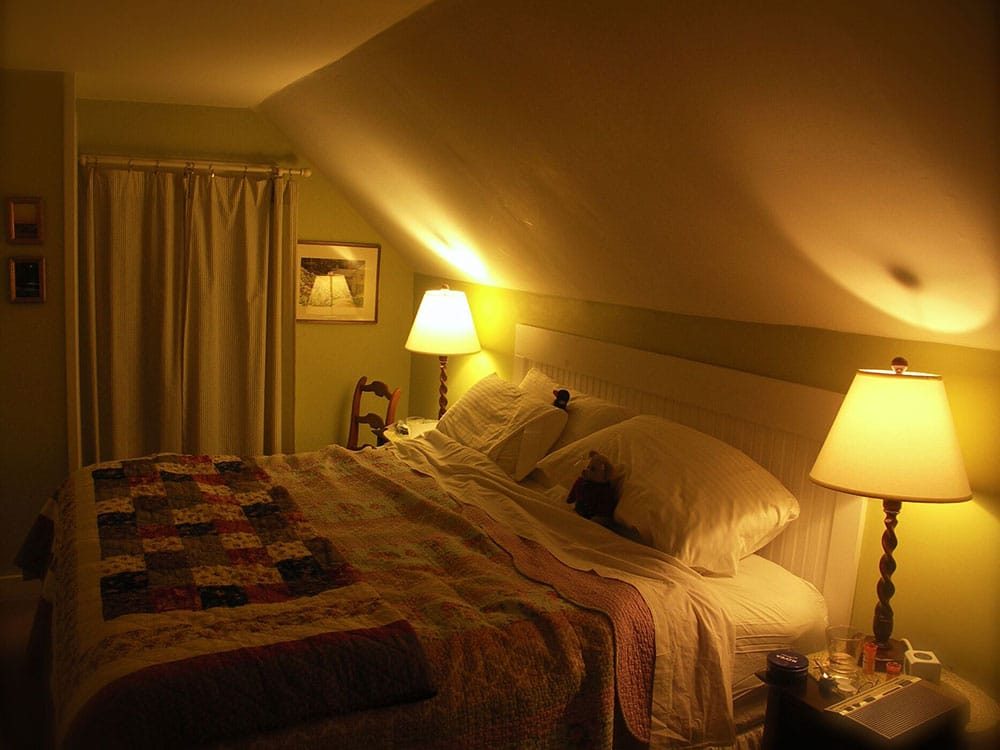 Master bedroom of the Ira Allen Suite at night. King size bed with a teddy bear on the pillow
