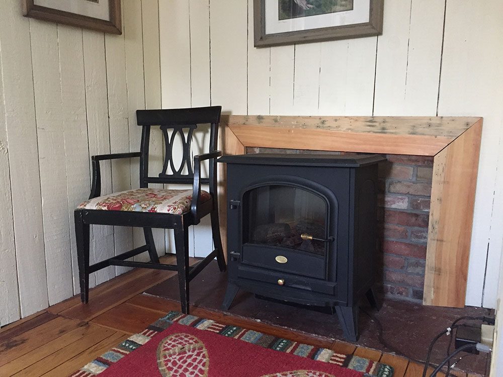 Electric fireplace and antique chair in the Ira Allen Suite