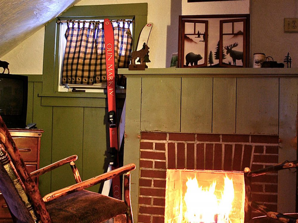 Roaring wood fire in the fireplace in the Remember Baker suite. two wooden-stick rockers in front of the fire.