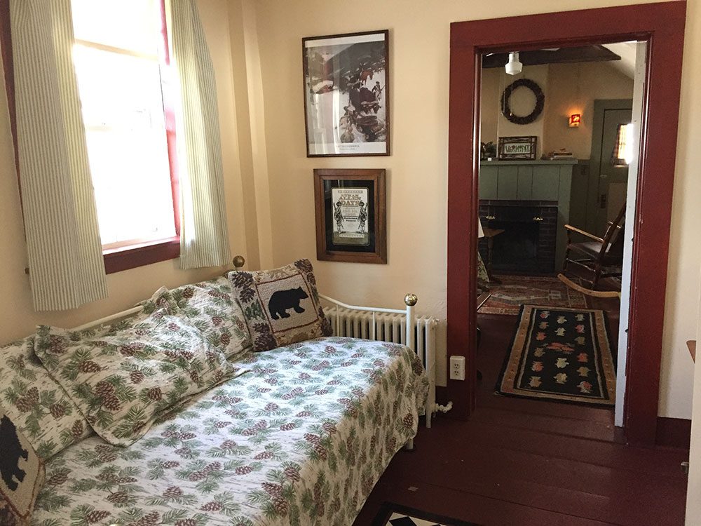 Smaller bedroom of the remember Baker suite with a metal-framed day bed with a pinecone print bedspread