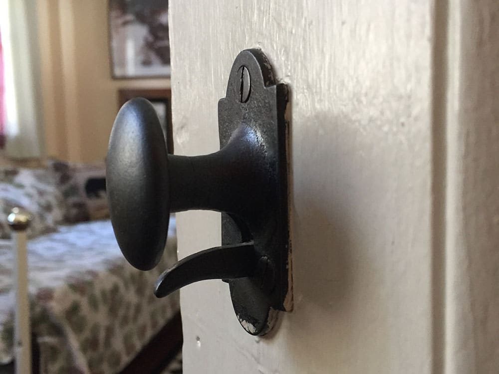 Antique, iron door latch on the door of Remember Baker Suite